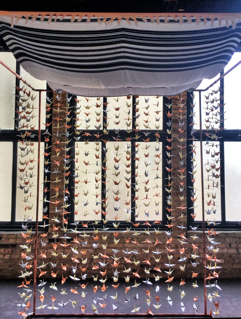 Jewish wedding chuppah with Japanese origami cranes hanging vertically from strings along the back and sides.