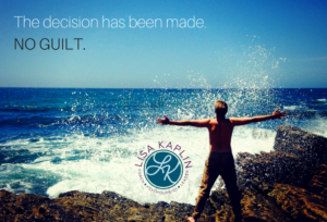 Wide shot of a person on the beach with their arms outstretched facing away from the camera and looking at the the breaking surf