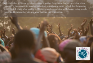 crowd at a large outdoor event holding up their open hands