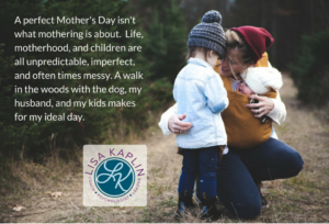 A photo of a white mother with her two white children, one a toddler and the other a baby she is carrying in a baby carrier, stopped in the woods so the mom can kneel down and hug the toddler.