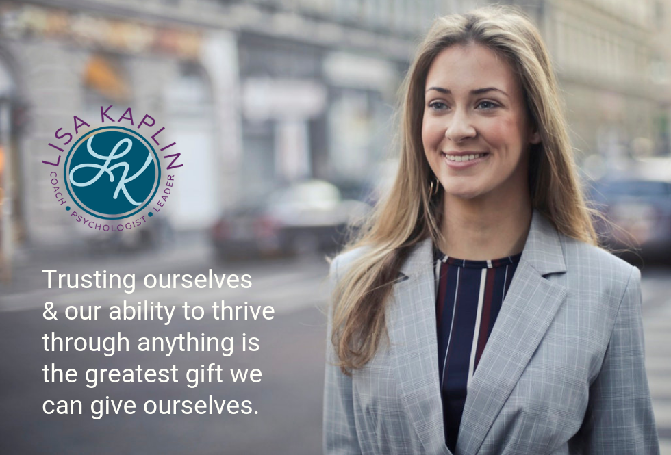 A color photo of a white woman in a business suit smiling while walking down a city streets. In the top left corner of the photo is the text “Trusting ourselves and our ability to thrive through anything is the greatest gift we can give ourselves.” The Lisa Kaplin logo is above the text.