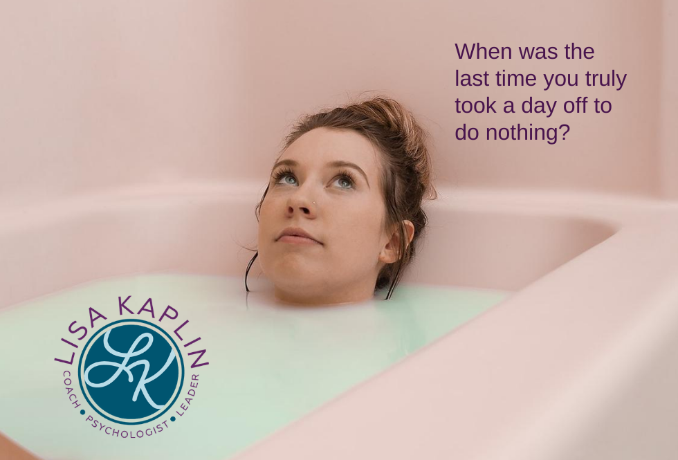 A color photo a young white woman soaking a pink bathtub of mint green water. The text at the top right of the image reads “When was the last time you truly took a day off to do nothing?” The Lisa Kaplin logo is in the bottom left corner.