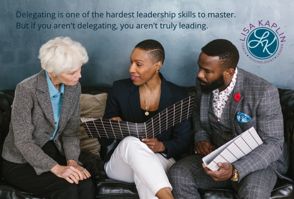 A color photo of three people in business attire looking over a document that the Black woman in the middle is explaining. to her left is a while woman with grey hair. To her right is a Black man with a beard. The text above them reads “Delegating is one of the hardest leadership skills to master. But if you aren't delegating, you aren't truly leading.” The Lisa Kaplin logo is in the top right corner.