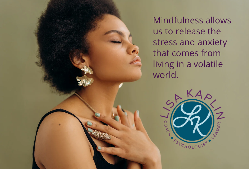 A color photo of a young, light-skinned Black woman with natural hair in profile. Her face is turned upward, her eyes are closed, and her hands are crossed over her chest in an embrace. The text on her right reads “Mindfulness allows us to release the stress and anxiety that comes from living in a volatile world.” The Lisa Kaplin logo is beneath the text.