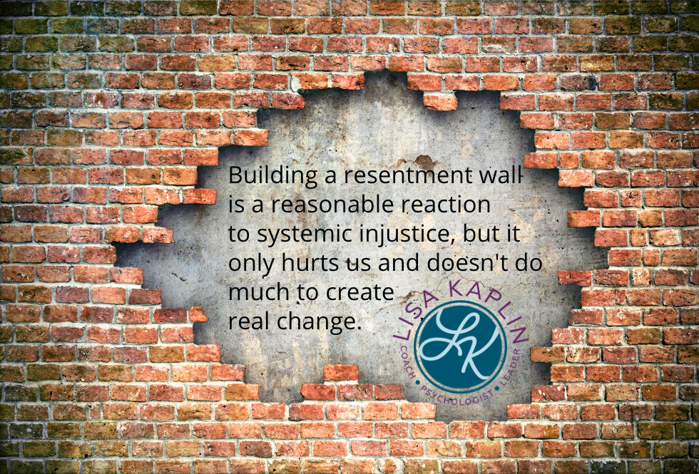 A color photo of a red brick wall with bricks missing in the middle exposing a grey cement wall underneath. The text positioned over the grey cement reads “Building a resentment wall is a reasonable reaction to systemic injustice, but it only hurts us and doesn't do much to create real change.“ The Lisa Kaplin logo is beneath the text.